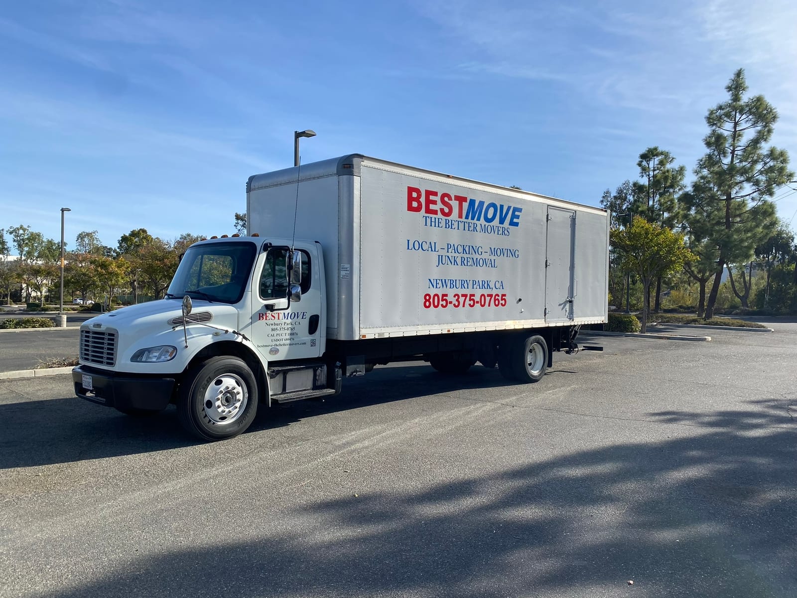 A white BEST MOVE box truck, lettered LOCAL PACKING MOVING JUNK REMOVAL, parked in the sun