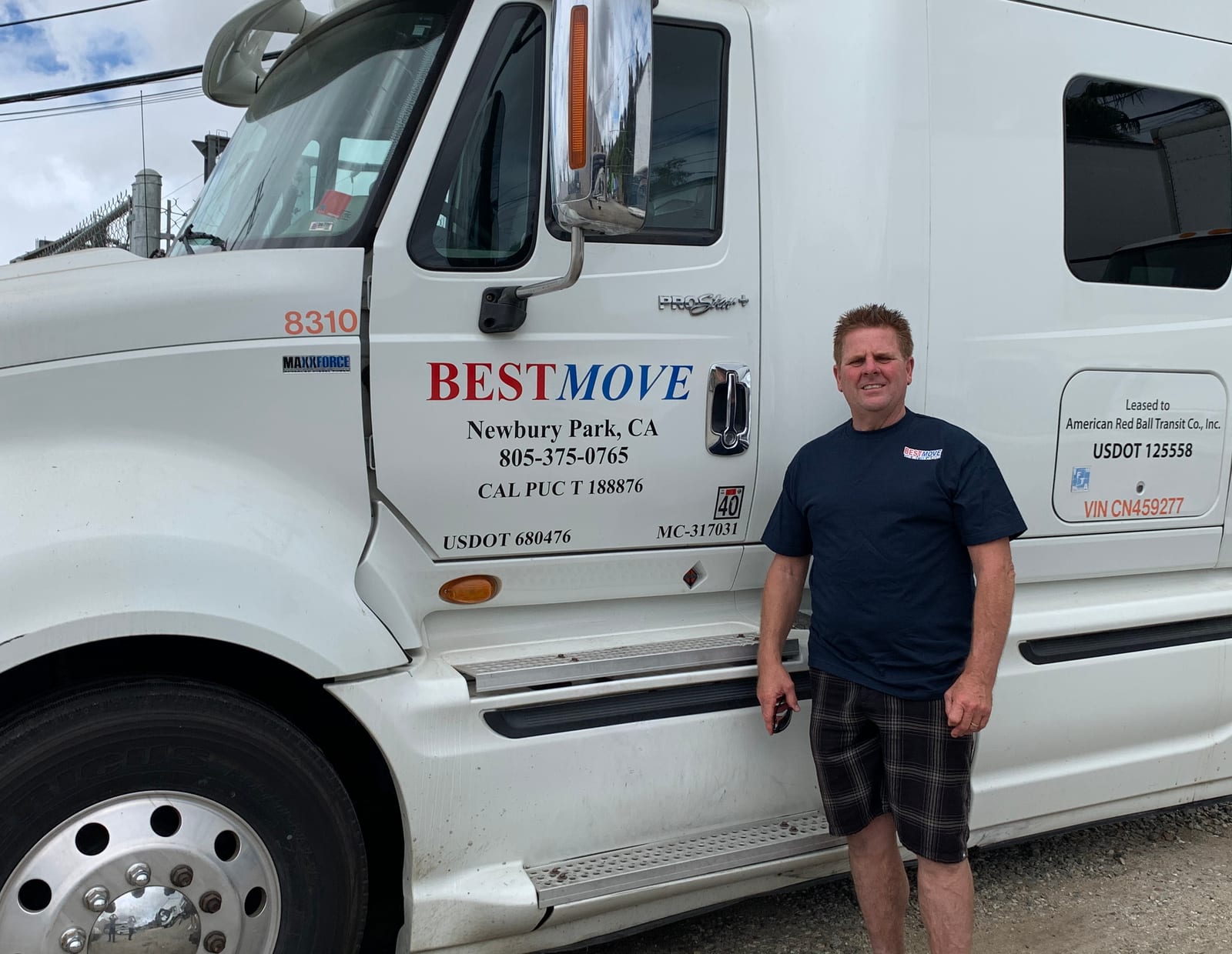 A BEST MOVE crew member standing beside the company's sleeper tractor, the cab door lettered BEST MOVE, Newbury Park, CA