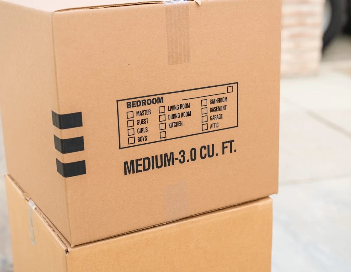 A BEST MOVE moving carton with the printed room checklist on the side — bedroom, living room, kitchen, garage