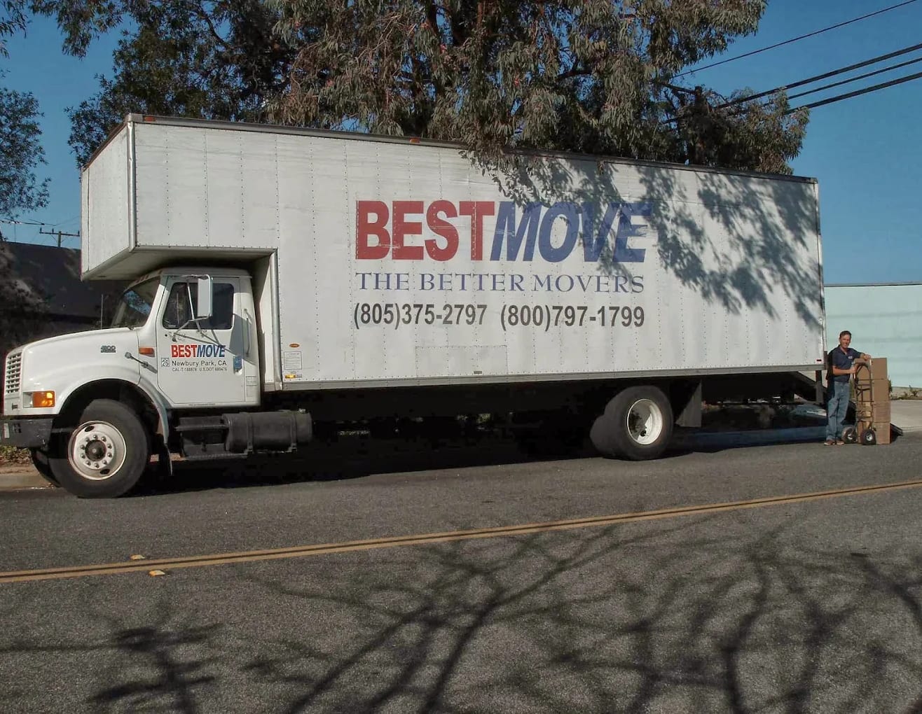 An earlier BEST MOVE box truck, lettered BEST MOVE — THE BETTER MOVERS, parked on a side street