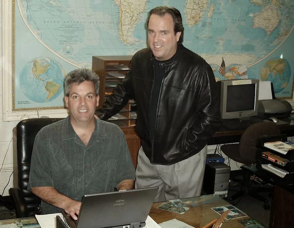Lyn and Gary in the BEST MOVE office in the company's earlier years, a world map behind the desk